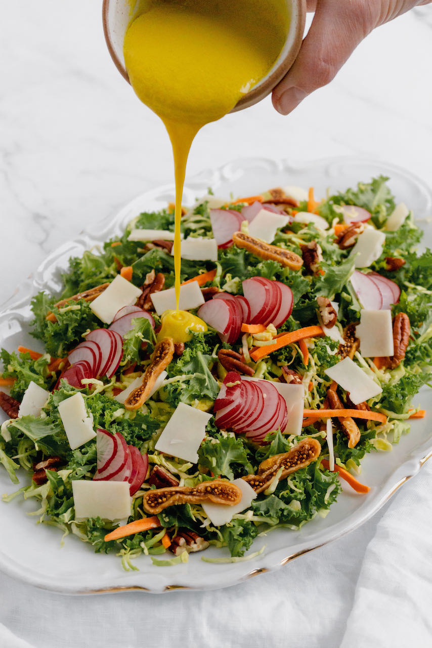 Kale & Brussels sprout salad pouring dressing