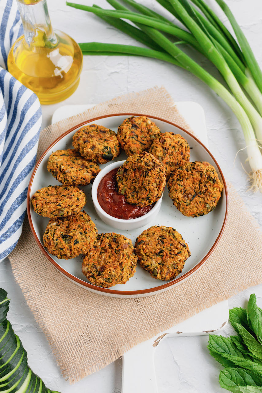 vegan zucchini carrot fritters in the sauce